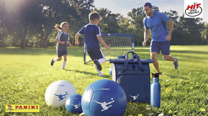 Fussballplatz mit Fussbaltor, Mann und zwei Kinder spielen Fussball